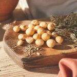 Noix de macadamia dorees sur une planche en bois rustique, lumiere chaude mediterraneenne