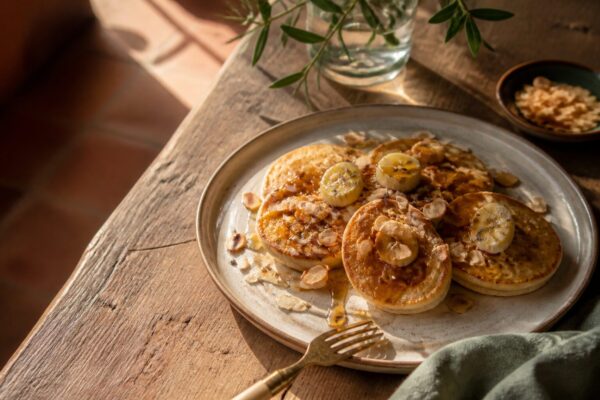 Pancake banane moelleux avec miel de lavande et amandes effilées sur table provençale