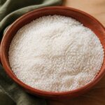 Un bol de riz cru pesé sur une balance de cuisine en bois, lumière naturelle chaude