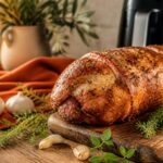 Roti de porc air fryer dore aux herbes de Provence sur planche en bois rustique