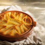 Clafoutis aux poires doré dans un plat terracotta sur torchon lin