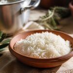 Riz basmati cuit en grains séparés dans un bol en terre cuite, lumière de cuisine chaude et dorée
