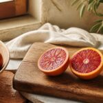 Orange sanguine coupée en deux sur une planche en bois, pulpe rouge carmin lumineuse