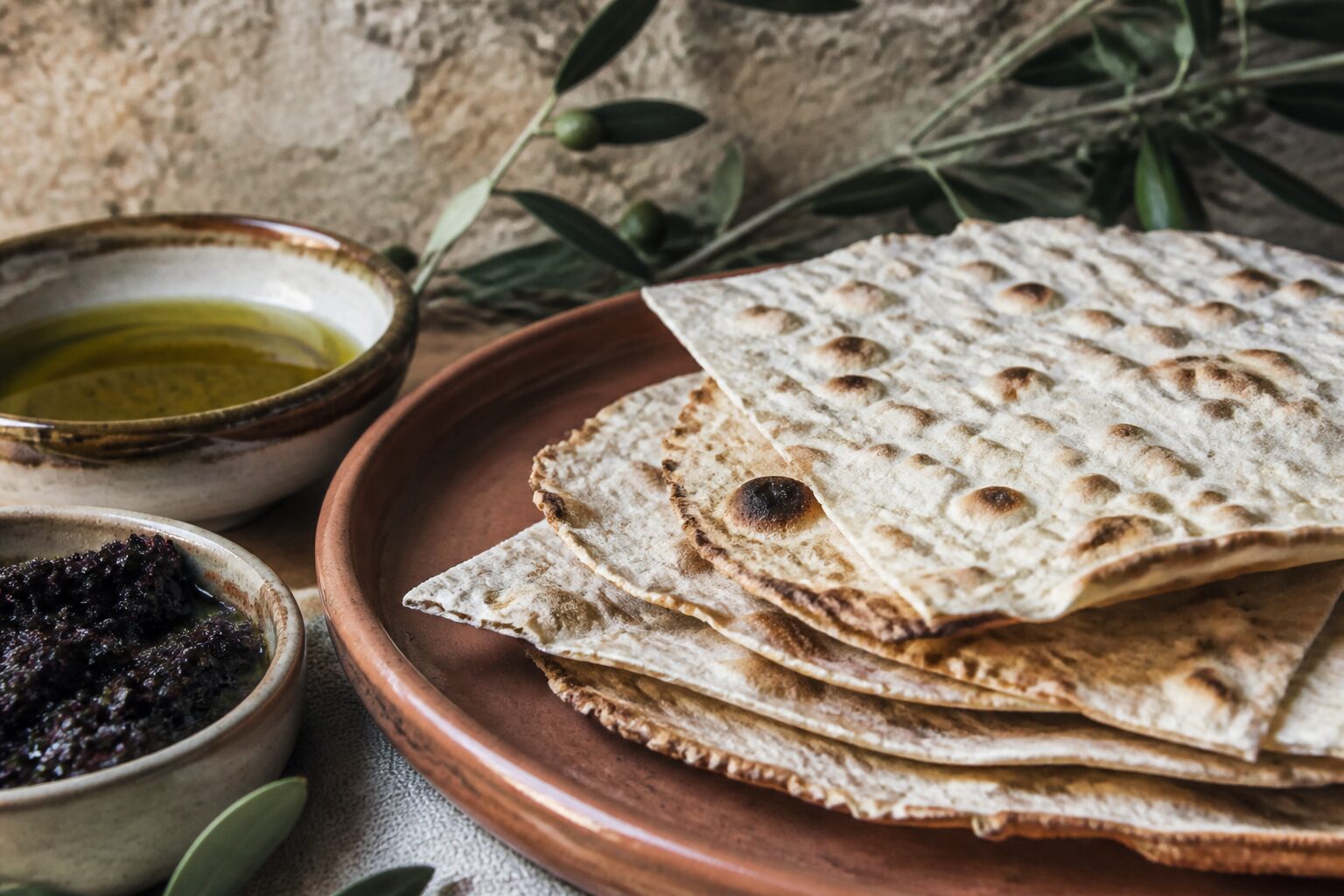 Galettes de pain azyme maison avec tapenade et huile d'olive sur nappe de lin