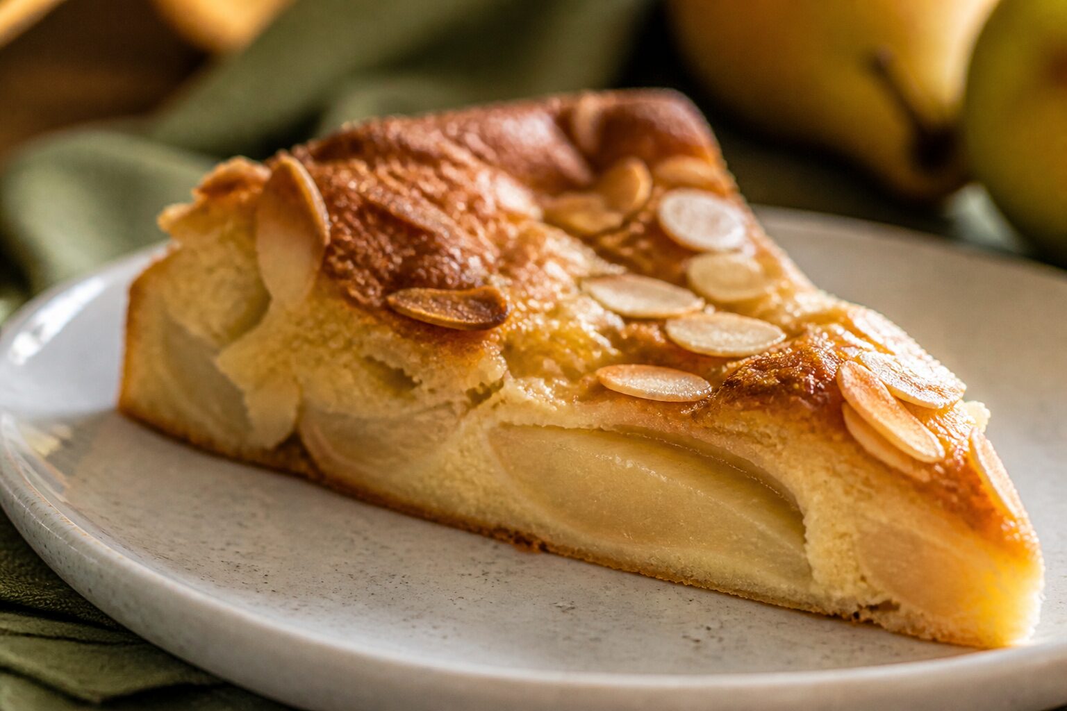 Part de clafoutis aux poires moelleux avec amandes effilées dans une assiette en grès