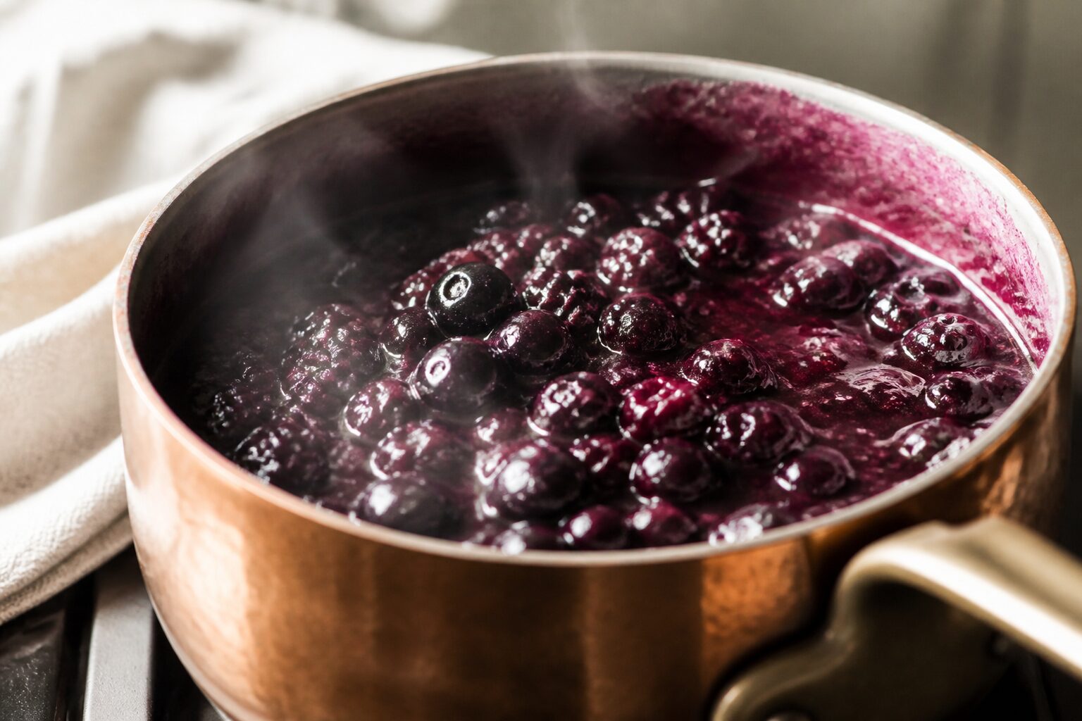 Coulis de myrtilles et de mûres qui mijote dans une casserole en cuivre