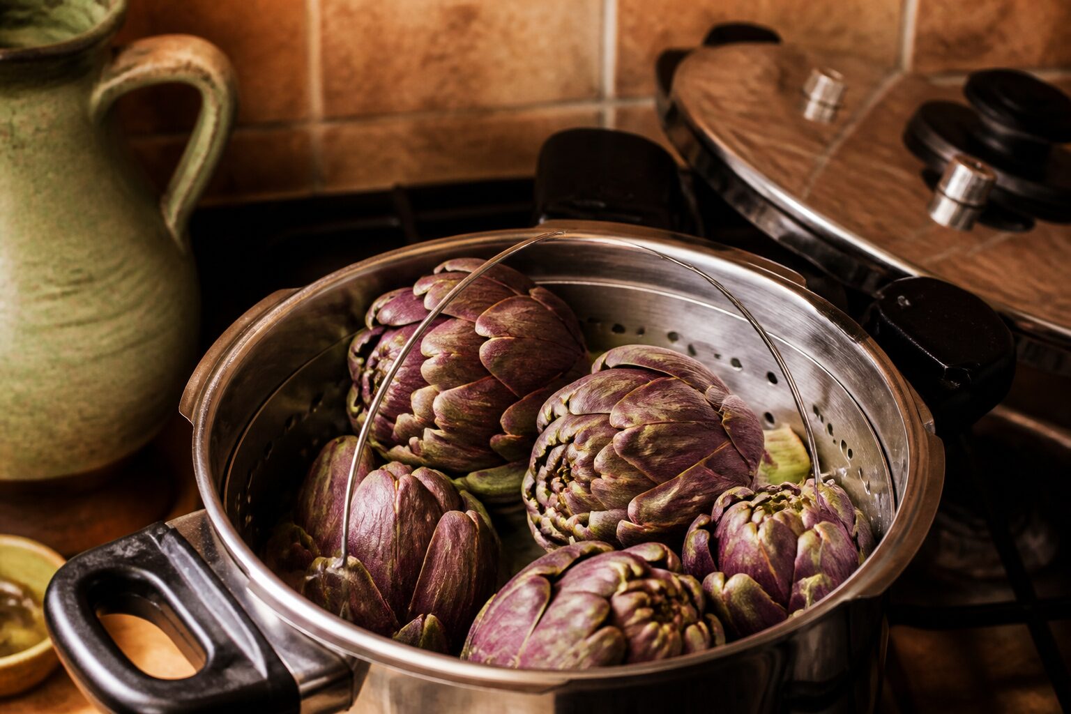 Cocotte minute ouverte avec panier vapeur et artichauts prêts à cuire