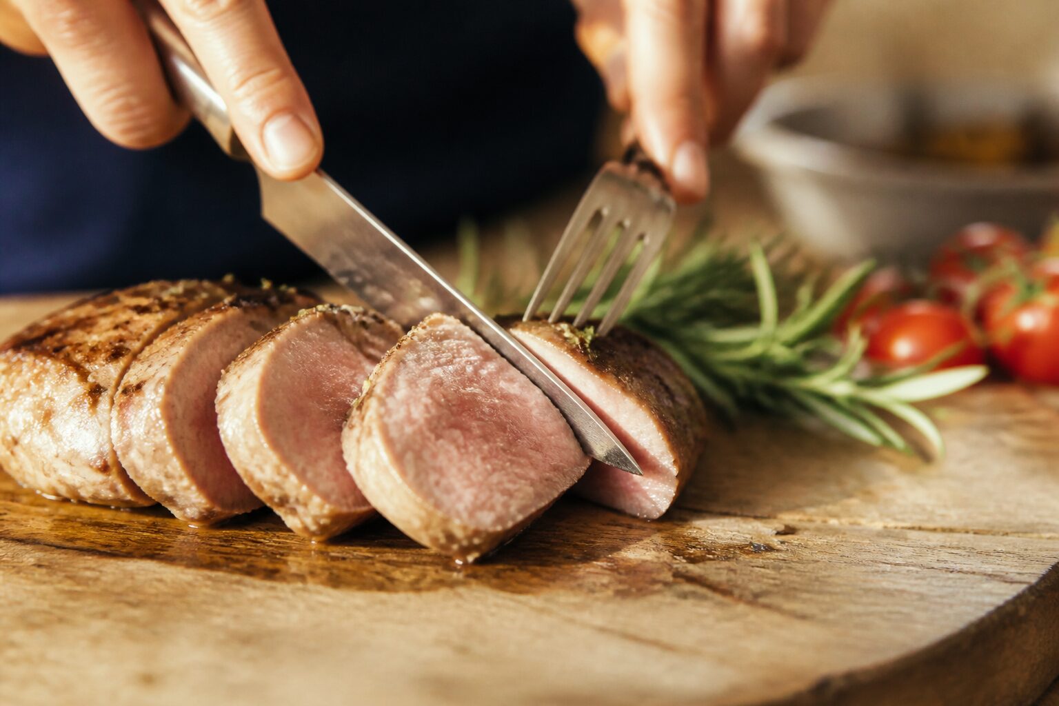 Filet mignon de porc tranché moelleux sur planche en bois avec romarin