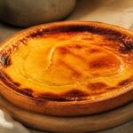 flan parisien entier doré sur planche en bois, lumière naturelle chaude