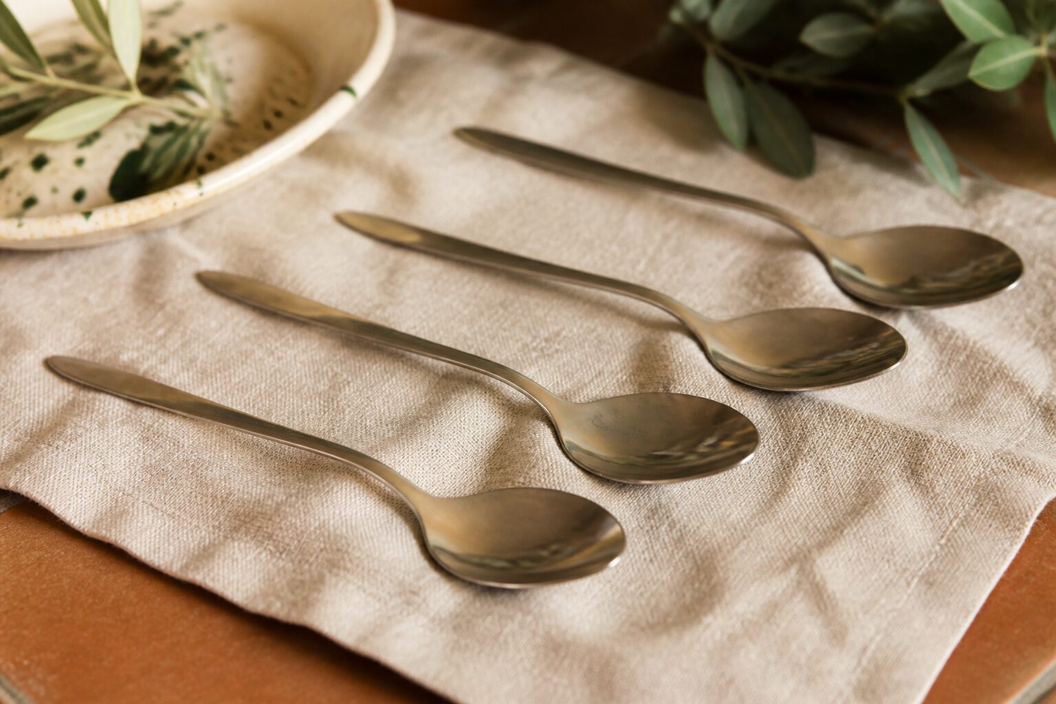 Cuillères à soupe en inox alignées sur un torchon de lin pour mesurer 250 ml sans doseur