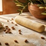 Boudin de pâte d'amande maison sur un plan de travail en bois avec amandes entières et sucre glace