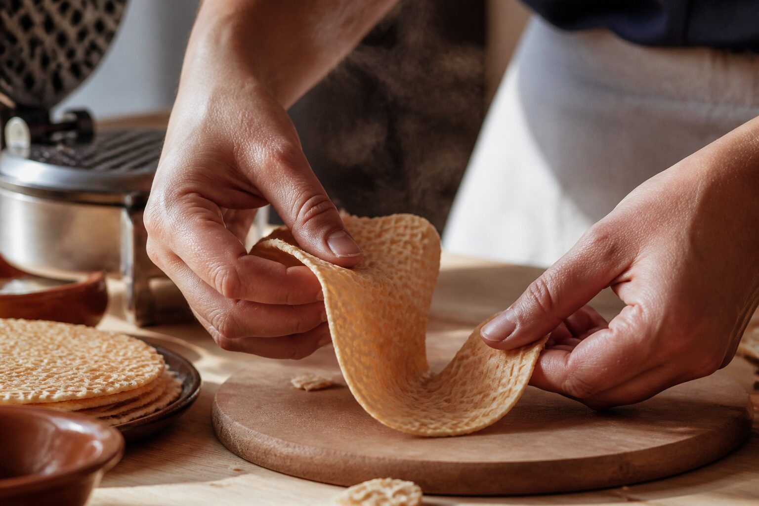 Mains façonnant une pâte à gaufrette souple à la sortie du gaufrier