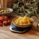 Quantité de pâtes par personne mesurée à la balance dans une cuisine lumineuse