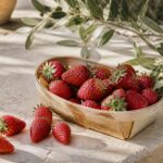 Barquette de fraises Gariguette rouges sur une table de marché provençal ensoleillé