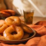 Sfenj, beignets maghrébins en anneau dorés nappés de miel sur assiette en terre cuite