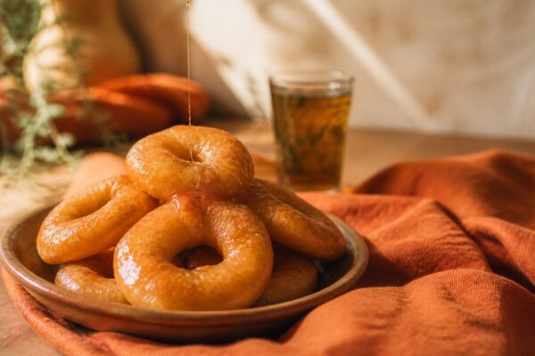 Sfenj, beignets maghrébins en anneau dorés nappés de miel sur assiette en terre cuite