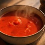 bol de soupe tomate grand-mère fumante posé sur une table en bois