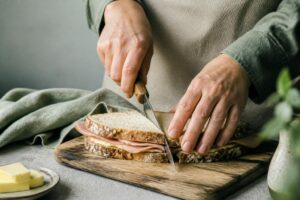 Mains tranchant un sandwich jambon beurre fraîchement préparé