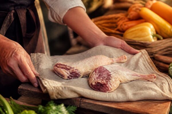 Manchons de canard crus présentés sur un torchon en lin au marché