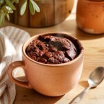 Mug cake au chocolat sans oeuf fondant dans une tasse en céramique terracotta