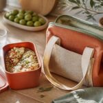 Sac isotherme repas posé sur une table de cuisine lumineuse à côté d'une boîte à repas