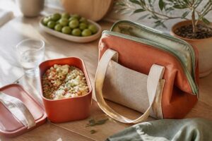 Sac isotherme repas posé sur une table de cuisine lumineuse à côté d'une boîte à repas